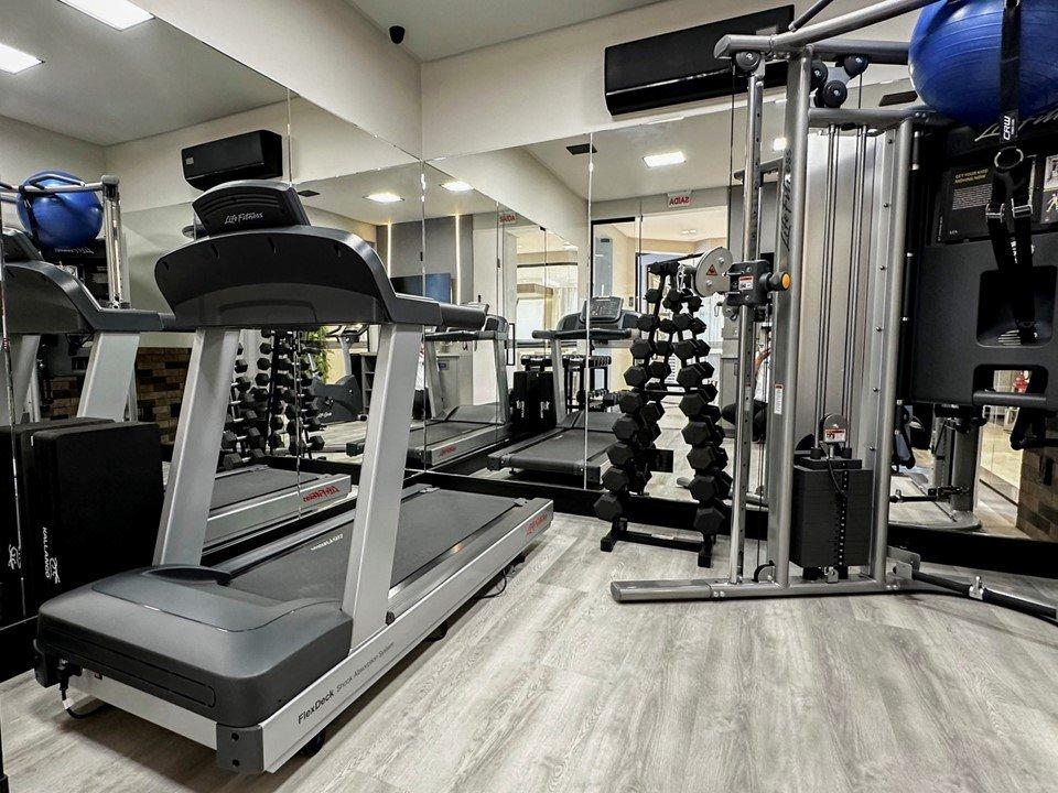 Espaço fitness do Long Beach Residence, equipado com esteiras e pesos