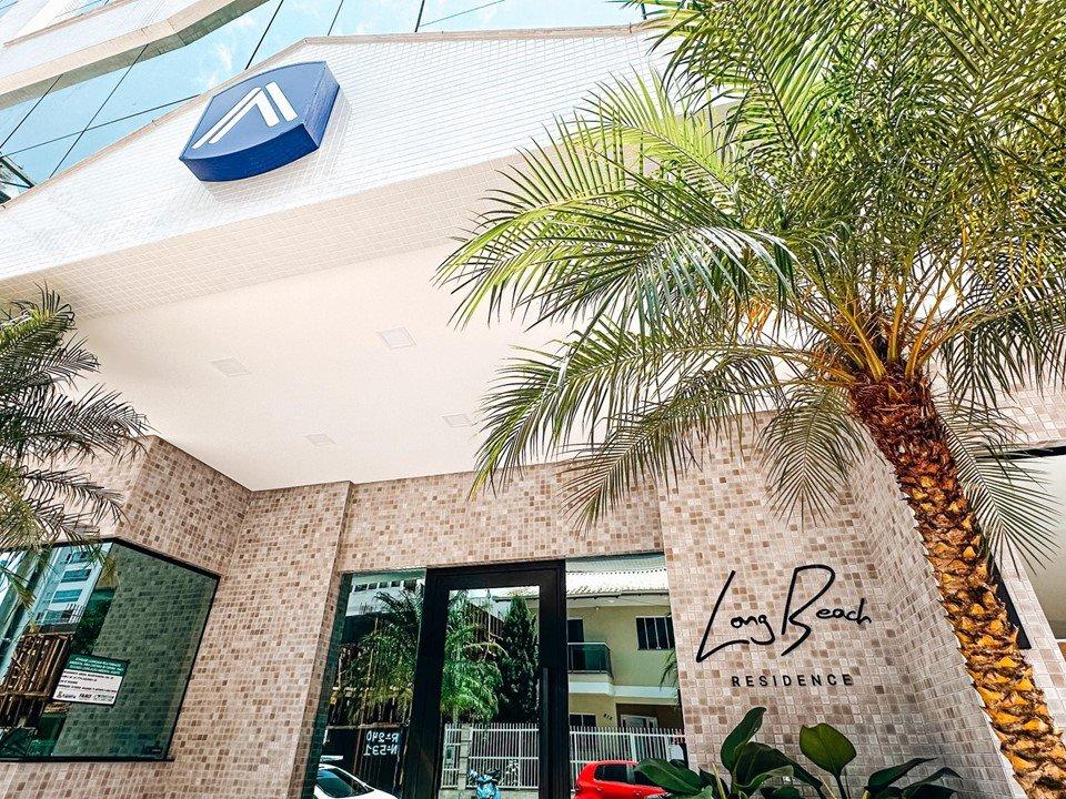 Entrada do Long Beach Residence, com palmeira e letreiro na fachada em pastilha